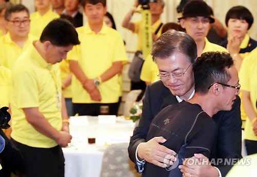 遺族の男性を抱擁する文大統領＝１６日、ソウル（聯合ニュース）