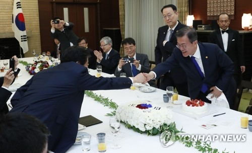 安倍首相（左）からケーキを贈られ、笑顔を浮かべる文大統領＝９日、東京（聯合ニュース）