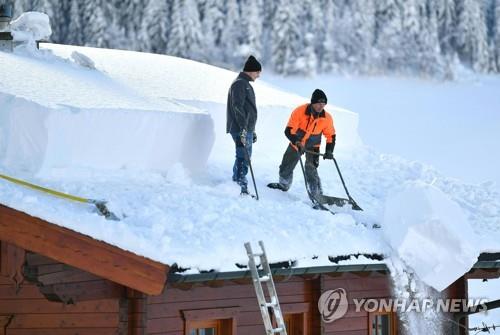 오스트리아 운터타우어른에서 11일(현지시간) 두 사람이 지붕 위의 눈을 치우고 있다. [AFP=연합뉴스]