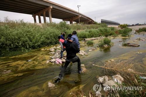 2019년 5월 7일 이민자가 어린이를 안고 미국과 멕시코의 국경 지대에 있는 브라보 강을 건너고 있다. [로이터=연합뉴스 자료사진]