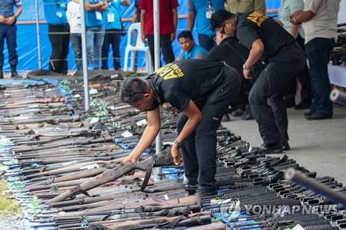 필리핀 남부 최대 이슬람 반군 MILF 조직원들이 반납한 무기를 살펴보는 관계자들