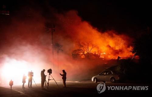 31일(현지시간) 미 캘리포니아주 샌버나디노의 힐사이드 파이어 화재 현장에서 언론 관계자들이 화재 상황을 보도하고 있다. [AFP=연합뉴스]