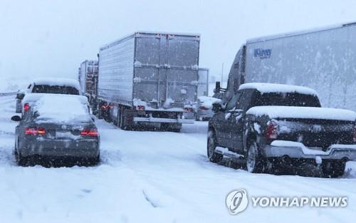 26일(현지시간) 미 캘리포니아 LA에서 라스베이거스로 이어지는 15번 주간 고속도로상 카혼 패스 인근에서 차들이 눈에 갇혀 정체돼 있다. [AP=연합뉴스]