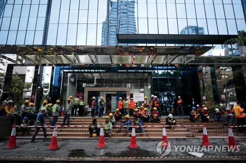 방콕 시내 수리 중인 건물 앞에서 쉬고 있는 근로자들 (자료사진)