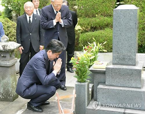 2014년 8월 12일 아베 신조 당시 일본 총리가 일본 야마구치(山口)현에 있는 외조부 기시 노부스케(岸信介·1896∼1987) 전 총리의 묘 앞에서 두 손을 모으고 있다. [교도=연합뉴스 자료사진]