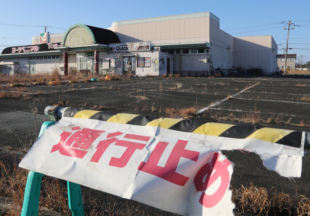 (후쿠시마=연합뉴스) 이세원 특파원 = 3일 오후 일본 후쿠시마현 도미오카마치의 귀환곤란구역의 방치된 슈퍼마켓 앞에 통행금지를 알리는 표지가 훼손돼 있다.