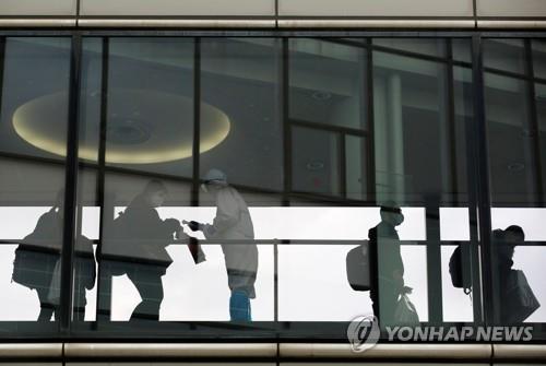 (나리타 로이터=연합뉴스) 일본 수도권 관문인 나리타국제공항에서 30일 신종 코로나바이러스 감염증(코로나19) 예방을 위해 방호복을 입은 공항 직원이 국제선 탑승객의 체온을 재고 있다. 
