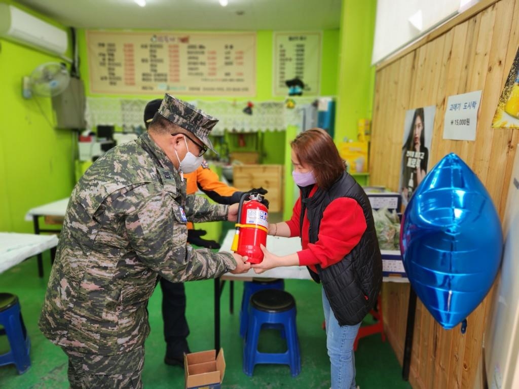 소화기를 지원한 상인에게 소화기를 건네는 최춘만 상사