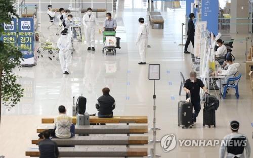 La foto de archivo, tomada el 5 de mayo de 2021, muestra a viajeros provenientes del exterior siguiendo las instrucciones de los trabajadores médicos en el Aeropuerto Internacional de Incheon, al oeste de Seúl.