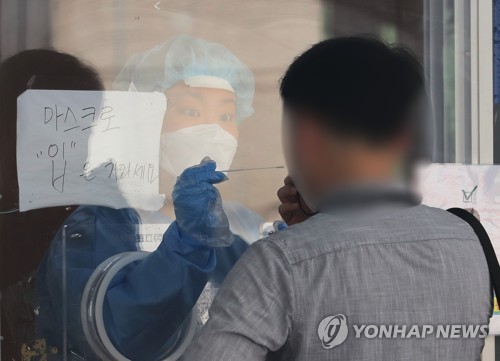 Una trabajadora médica, vestida con traje de protección, recolecta una muestra de un ciudadano para la prueba del coronavirus, el 8 de junio de 2021, en una clínica provisional, en Seúl.