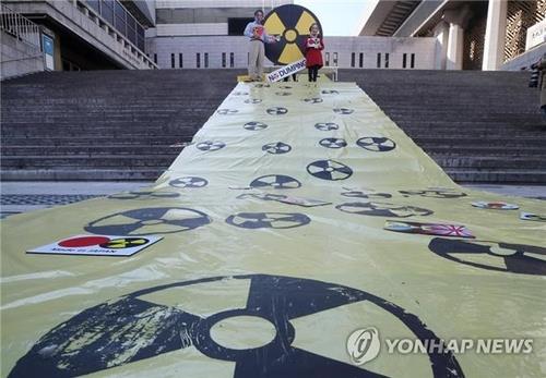 Los activistas surcoreanos celebran una manifestación en Seúl, el 25 de octubre de 2021, llevando máscaras que representan a los primeros ministros japoneses, en ejercicio y anteriores, para condenar el plan de Japón de verter agua radiactiva al mar desde su paralizada planta de energía nuclear de Fukushima.