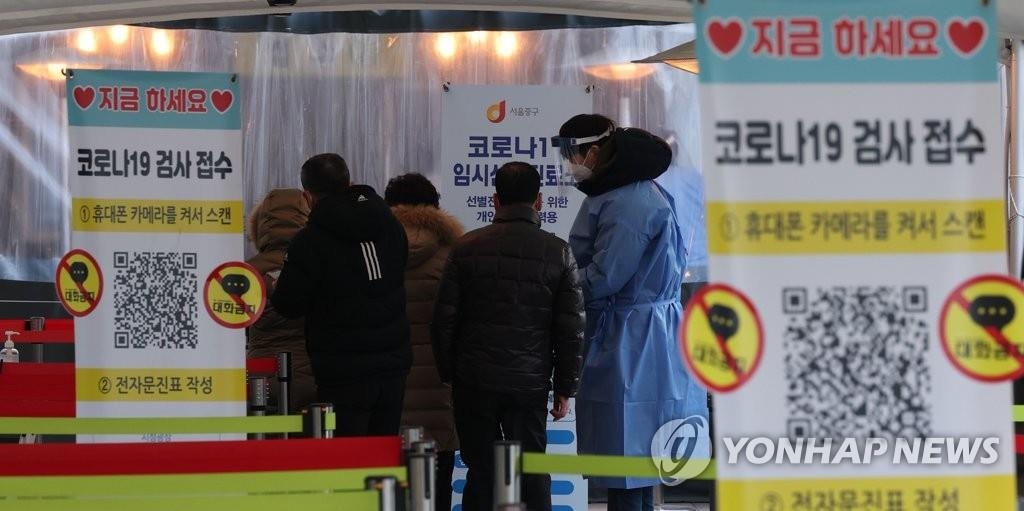Un trabajador médico guía a las personas que esperan en fila para ser sometidas a la prueba del COVID-19, el 5 de enero de 2022, en una clínica de exámenes frente a la Estación de Seúl, en la capital surcoreana.
