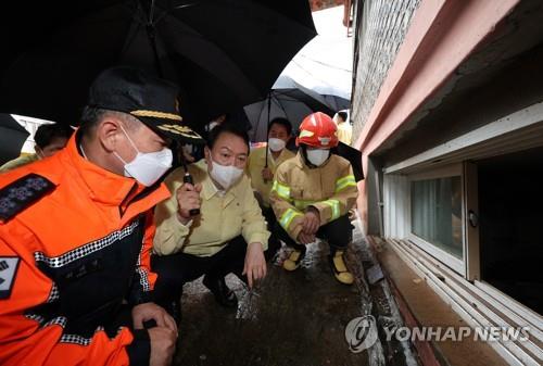 El presidente surcoreano, Yoon Suk-yeol (centro), realiza la inspección de una pequeña vivienda en semisótano, en Seúl, el 9 de agosto de 2022, ya que tres miembros de una familia que residía en el lugar fallecieron debido a una inundación repentina.