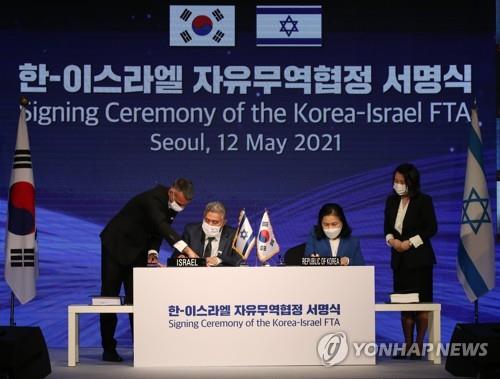 En la imagen de archivo, tomada el 12 de mayo de 2021, se muestra a la entonces jefa negociadora de comercio de Corea del Sur, Yoo Myung-hee (segunda por la dcha.), con su homólogo israelí, Amir Peretz (segundo por la izda.), firmando el tratado de libre comercio (TLC) entre ambos países.
