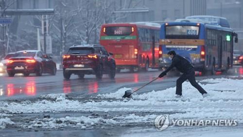 La foto de archivo, sin fechar, muestra a un trabajador quitando la nieve de una acera, en Seúl.