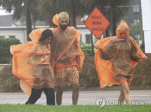 강한 바람과 함께 비가 쏟아지는 가운데 우비를 입고 이동하는 플로리다 주민들