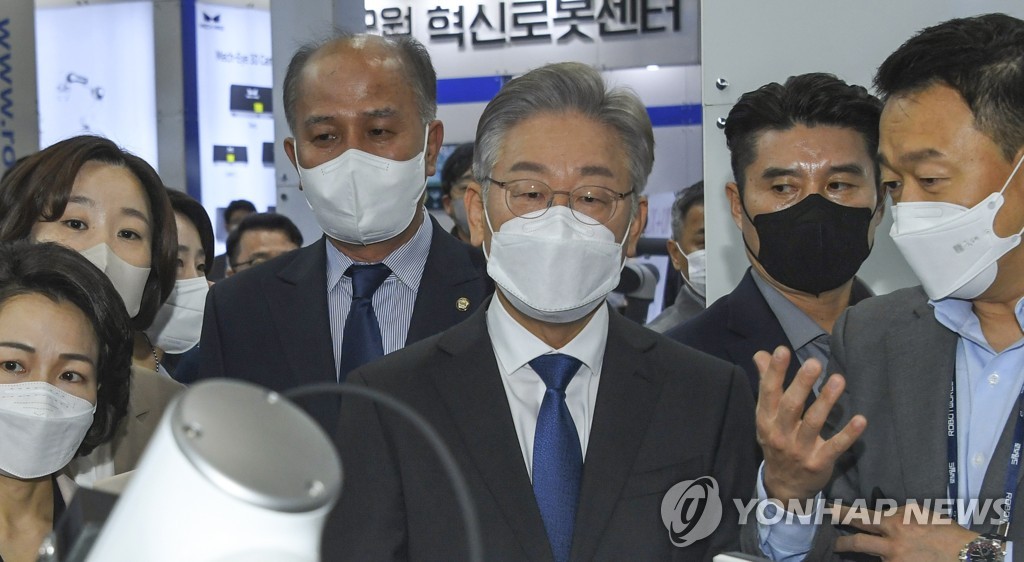 Lee Jae-myung (C), the presidential candidate of the ruling Democratic Party, looks at a robot demonstration at a robot fair in Goyang, northwest of Seoul, on Oct. 28, 2021. (Pool photo) (Yonhap)