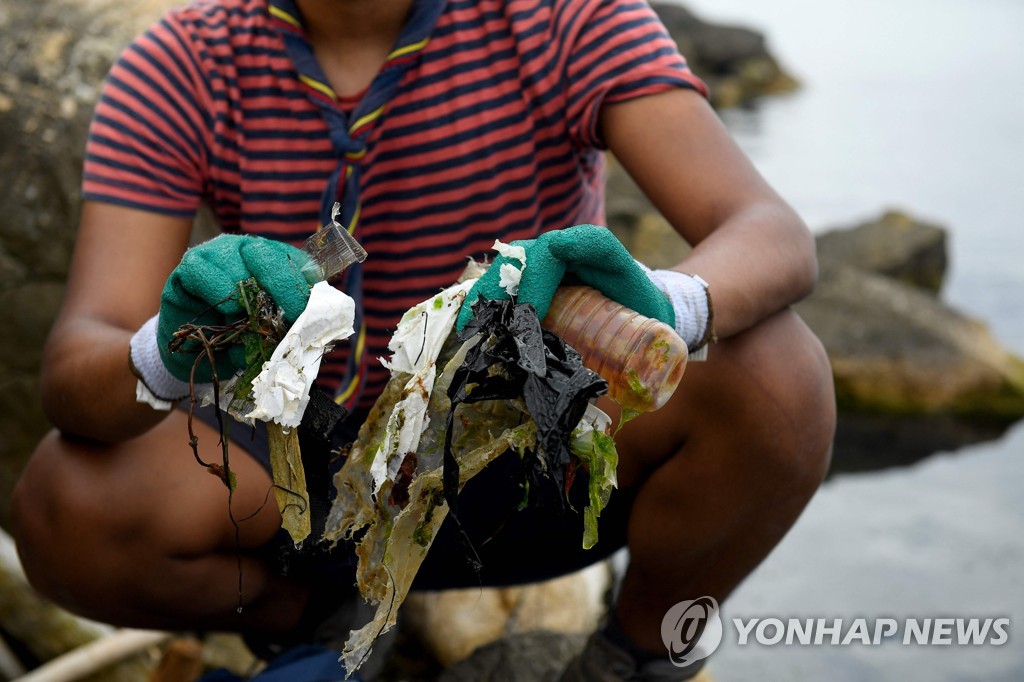 한 자원봉사자가 해양 플라스틱 쓰레기를 줍고 있다.