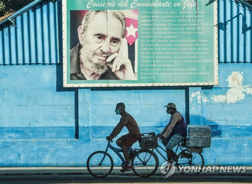 쿠바 사회주의 혁명을 주도한 피델 카스트로의 초상 아래를 아바나 시민들이 지나고 있다. [AFP=연합뉴스]