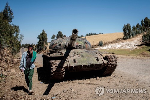 지난해 12월 내전으로 파괴된 탱크 옆을 걷는 에티오피아 젊은이.