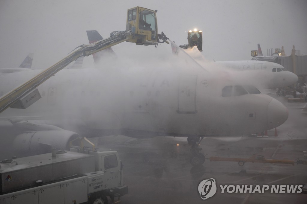 얼음 제거 작업을 진행 중인 항공사 직원들