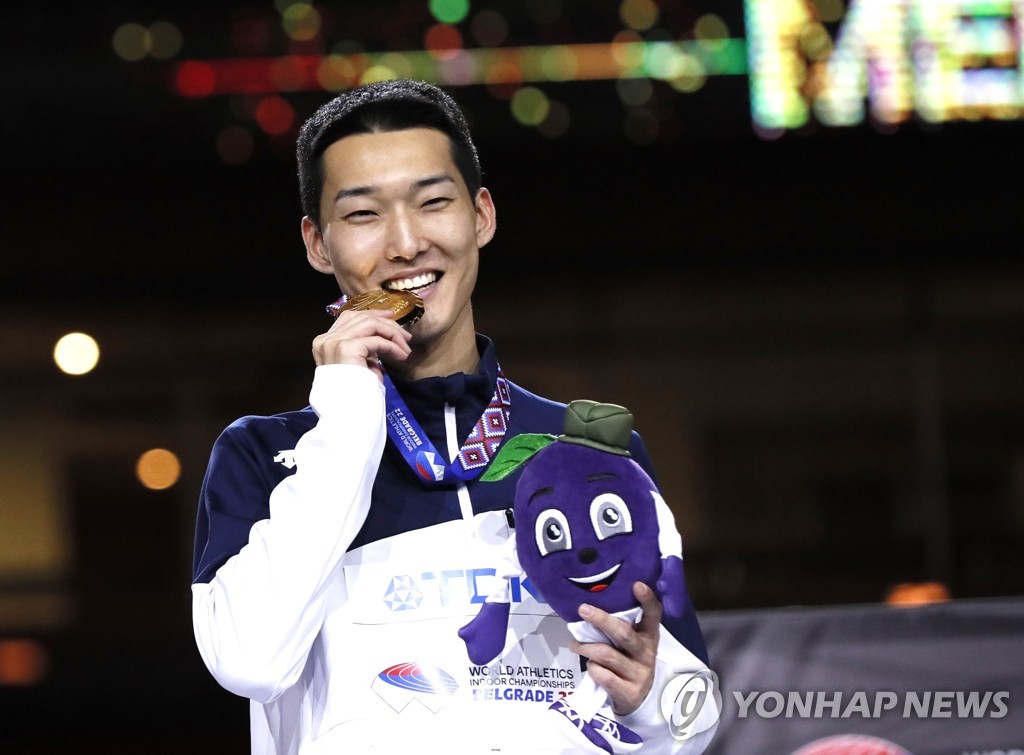In this EPA photo, Woo Sang-hyeok of South Korea bites his gold medal won in the men's high jump at the World Athletics Indoor Championships at Stark Arena in Belgrade on March 20, 2022. (Yonhap)