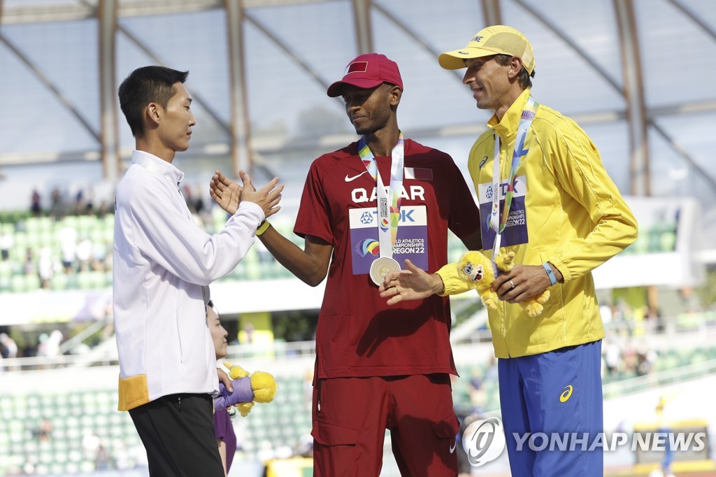 In this EPA photo, Woo Sang-hyeok of South Korea (L), silver medalist in the men's high jump at the World Athletics Championships, congratulates gold medalist Mutaz Essa Barshim of Qatar and bronze medalist Andriy Protsenko of Ukraine during the medal ceremony at Hayward Field in Eugene, Oregon, on July 19, 2022. (Yonhap)