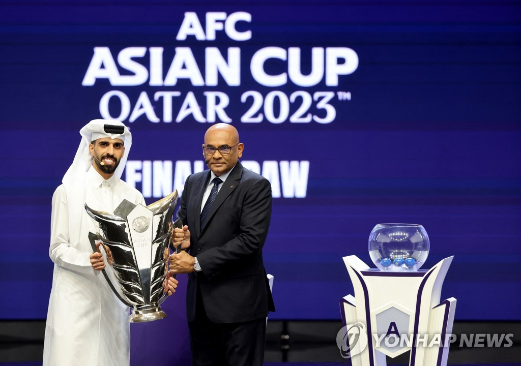이 Reuters 사진에서 카타르의 축구 선수 Hassan Al Haydos(왼쪽)가 카타르 오페라 하우스에서 열린 경기 조추첨 전에 AFC 아시안컵 트로피를 Datuk Seri Windsor John AFC 사무총장에게 전달하고 있습니다.  2023년 5월 11일 도하에서. (연합)