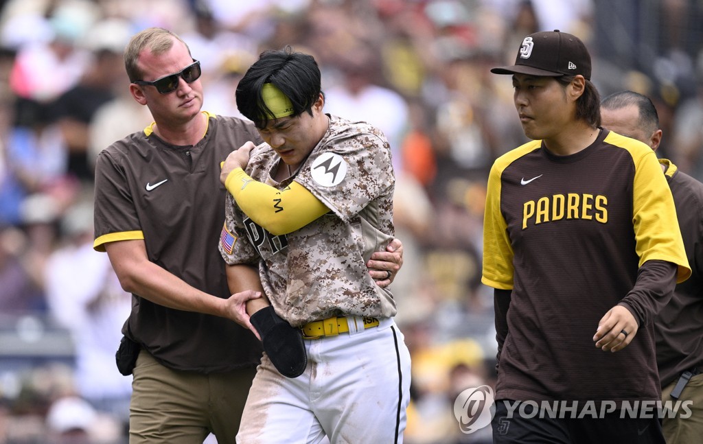 In this photo from USA Today Sports via Reuters, Kim Ha-seong of the San Diego Padres (C) is helped off the field by a team trainer after hurting his right shoulder on a slide home during the bottom of the third inning of a Major League Baseball regular season game against the Texas Rangers at Petco Park in San Diego on July 30, 2023. (Yonhap)