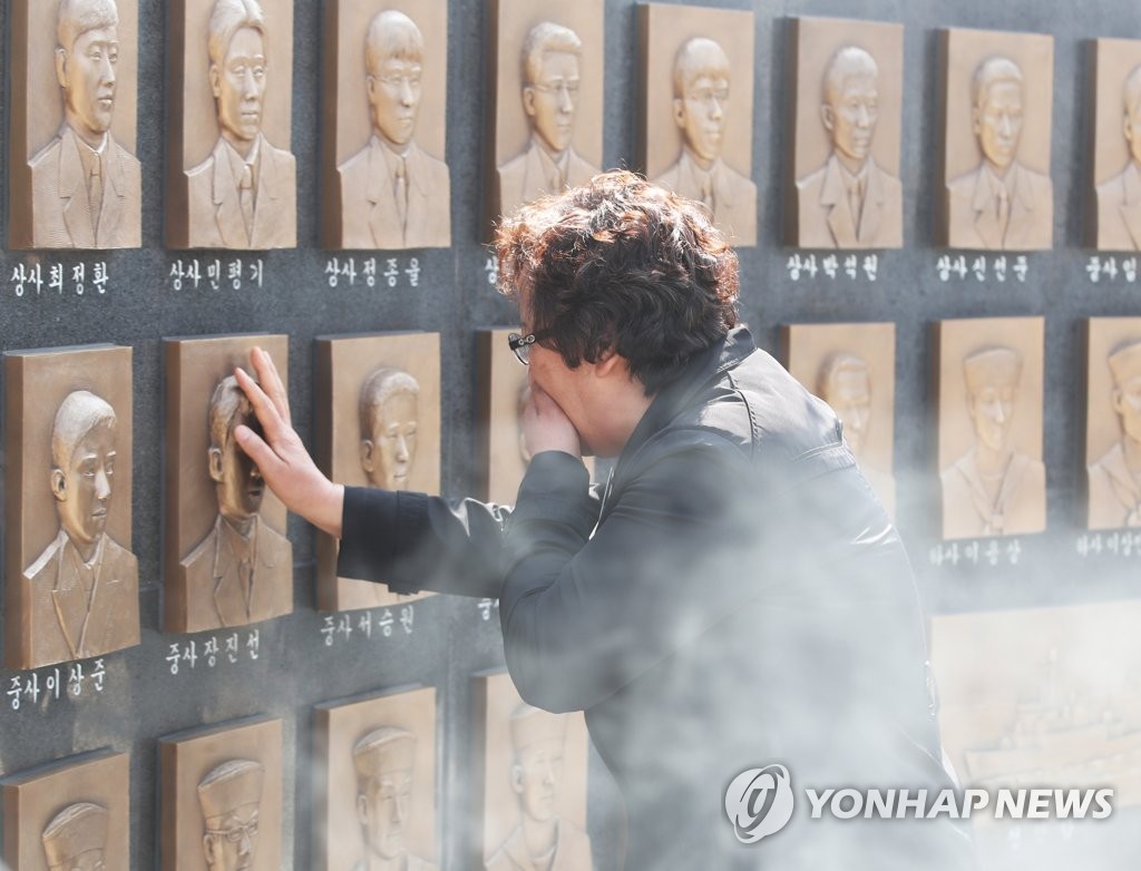 지난 2019년 3월경기도 평택시 해군 2함대 사령부에서 열린 천안함 46용사 추모식에서 한 유가족이 추모비에 새겨진 얼굴을 어루만지고 있다. [연합뉴스 자료사진]