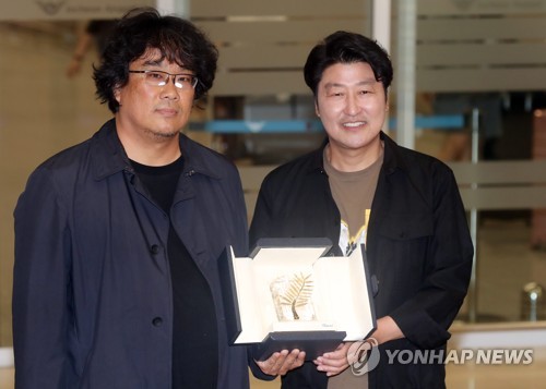 South Korean director Bong Joon-ho (L) and actor Song Kang-ho show off the Palme d'Or award during a meeting with reporters at Incheon International Airport, west of Seoul, on May 27, 2019, upon returning home from Cannes, France. Bong won the award for his film "Parasite" at the 72nd edition of the Cannes Film Festival the previous day. (Yonhap)
