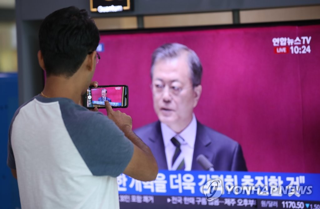 A foreign tourist films footage of President Moon Jae-in's budget speech, broadcast live, with his smartphone at Seoul Station on Oct. 22, 2019. (Yonhap)