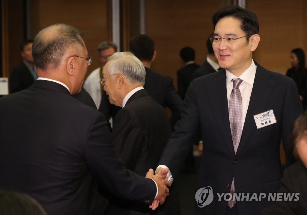 文在寅（ムン・ジェイン）大統領主宰の新年会で現代自動車グループの実質トップ、鄭義宣（チョン・ウィソン）総括首席副会長と握手を交わす李在鎔氏（右）＝２日、ソウル（聯合ニュース）