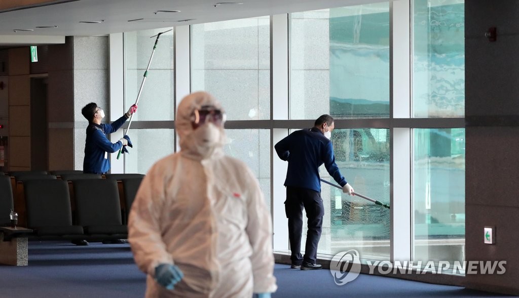 仁川空港の入国検査場の窓を清掃する係員ら＝２９日、仁川（聯合ニュース）