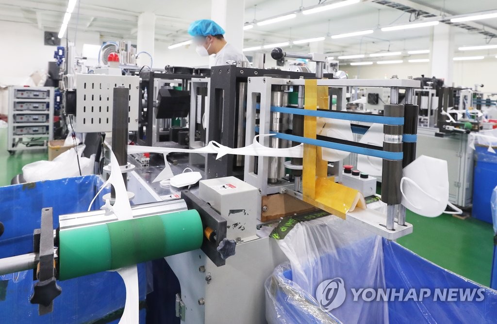 In this file photo, taken on March 9, 2020, a worker checks a production line for masks at a facility in Yongin, just south of Seoul. (Yonhap)