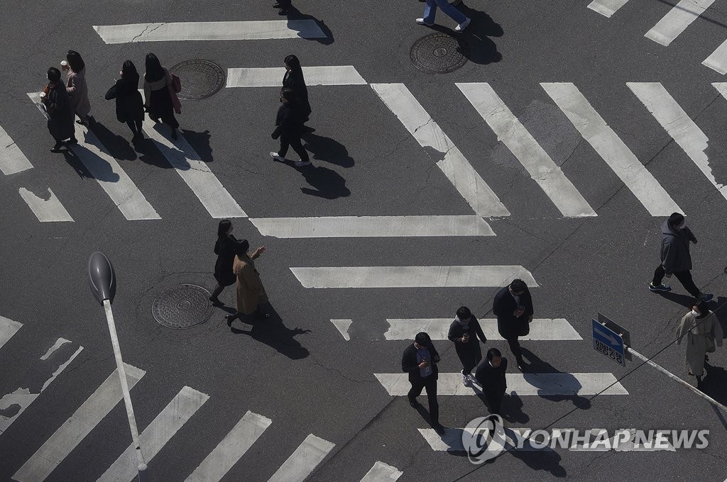 People cross a street junction in Seoul on March 24, 2020. (Yonhap) 