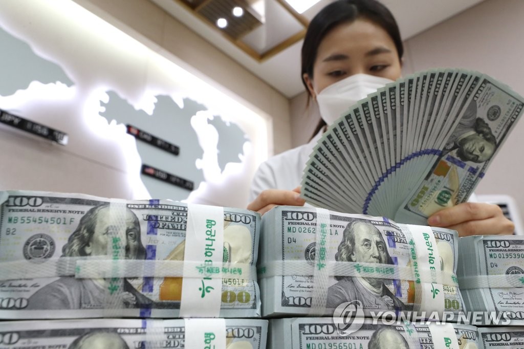 The photo, taken March 31, 2020, shows a bank official inspecting U.S. dollars at a Seoul bank. (Yonhap)