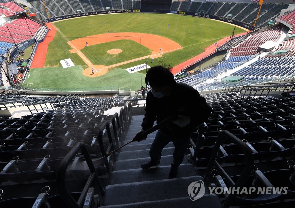 A public health work sanitizes seats at an empty Jamsil Stadium in Seoul during a Korea Baseball Organization preseason game between the LG Twins and the SK Wyverns on April 24, 2020. (Yonhap)