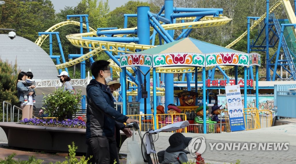 Visitors wearing masks walk around an amusement park in Seoul on April 29, 2020. (Yonhap)