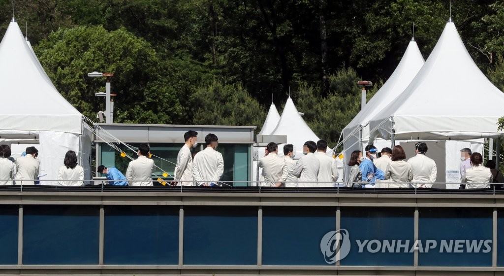 Hospital officials and health workers of Samsung Medical Center in southern Seoul line up at an outdoor testing center on May 19, 2020, to receive tests for the new coronavirus. (Yonhap)