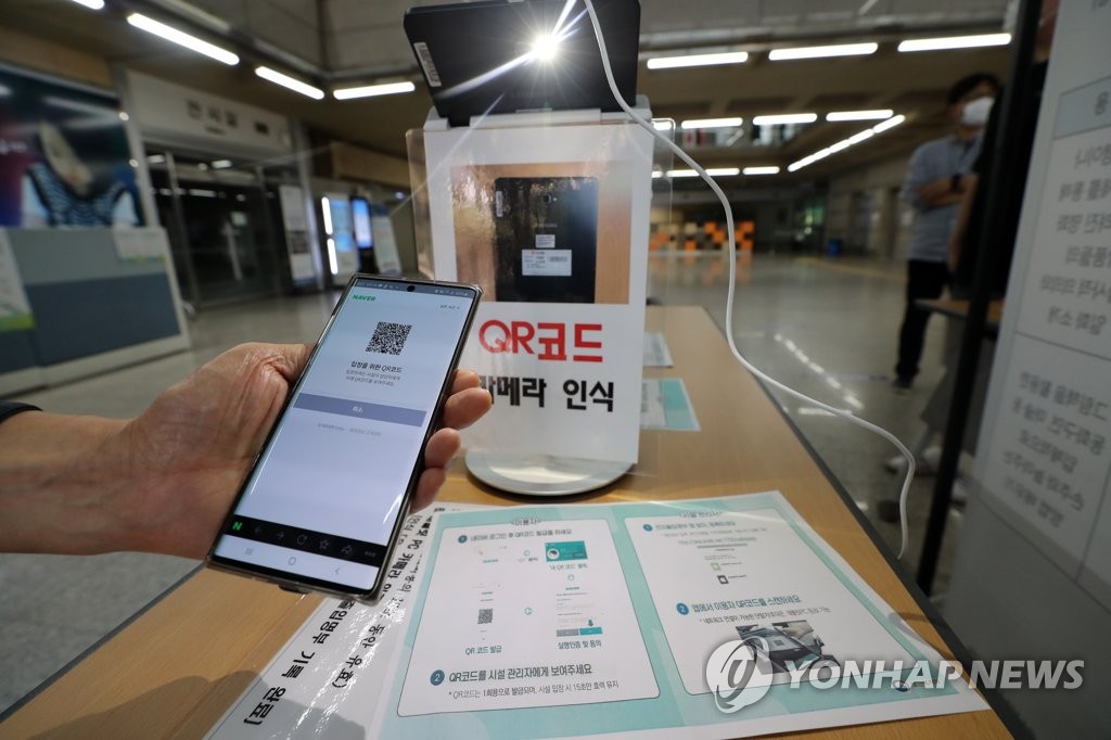 A visitor uses a quick response (QR) code-based registration system to enter a library in Daejeon, 164 kilometers south of Seoul, on June 2, 2020. (Yonhap)