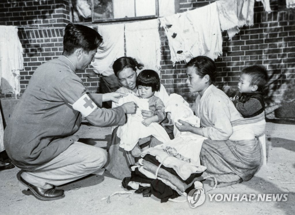 A Red Cross official hands out clothes to Korean War refugees at an elementary school in Seoul, in this photo taken by the International Committee of the Red Cross (ICRC)/Sgt. 1st Class Al Chang on Nov. 2, 1950. Yonhap News Agency obtained 70 such black-and-white photographs from the ICRC and published them on June 24, 2020, in time for the 70th anniversary of the outbreak of the 1950-53 Korean War. (PHOTO NOT FOR SALE) (Yonhap)