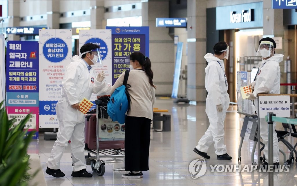 Quarantine officials inform an international arrival about transportation options at Incheon International Airport, South Korea's main gateway, west of Seoul, on July 29, 2020. (Yonhap)
