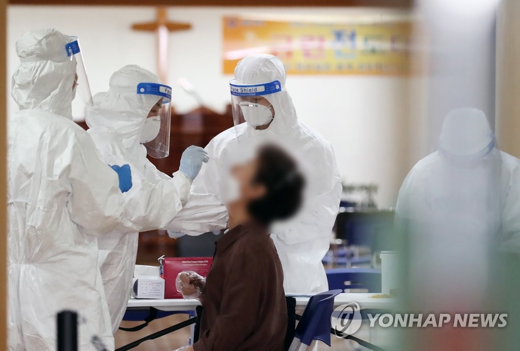 Health workers test a visitor at a temporary screening center set up at Kumnan Church in eastern Seoul on Aug. 19, 2020, after a church member who tested positive for the new coronavirus was found to have visited Sarang Jeil Church. (Yonhap)