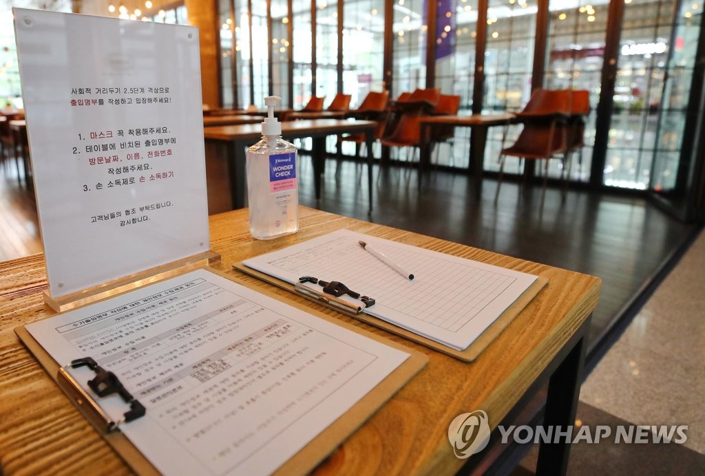 An entry log, hand sanitizer and a sign asking customers to fill out the form is seen at a cafe in Gangnam in southern Seoul on Aug. 31, 2020. (Yonhap)