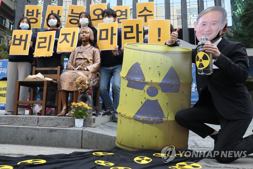 ソウルの日本大使館前で「放射能汚染水を捨てるな」と書かれたカードを掲げる環境団体＝（聯合ニュース）