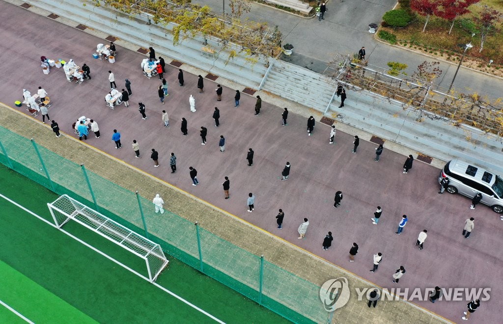 Students keep a distance from one another while waiting in line to receive COVID-19 tests at a makeshift virus testing clinic at a middle school in Gwangju on Nov. 26, 2020. (Yonhap)
