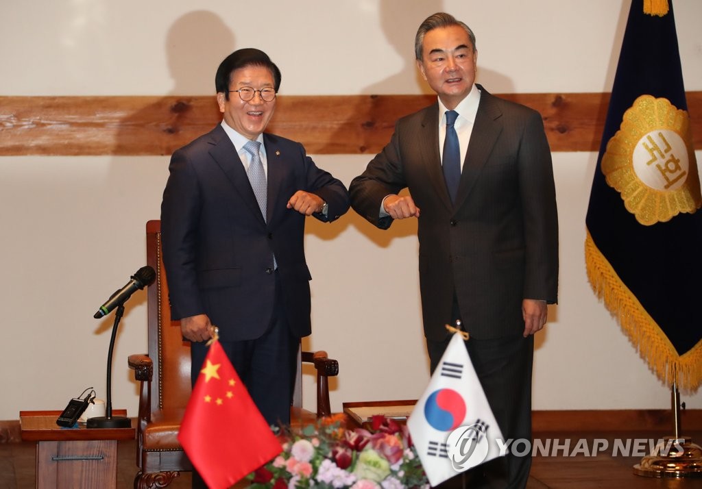El presidente de la Asamblea Nacional, Park Byeong-seug (izda.), saluda con el codo al ministro de Asuntos Exteriores chino, Wang Yi, antes de comenzar sus conversaciones, el 27 de noviembre de 2020, en la Asamblea Nacional, en Seúl.
