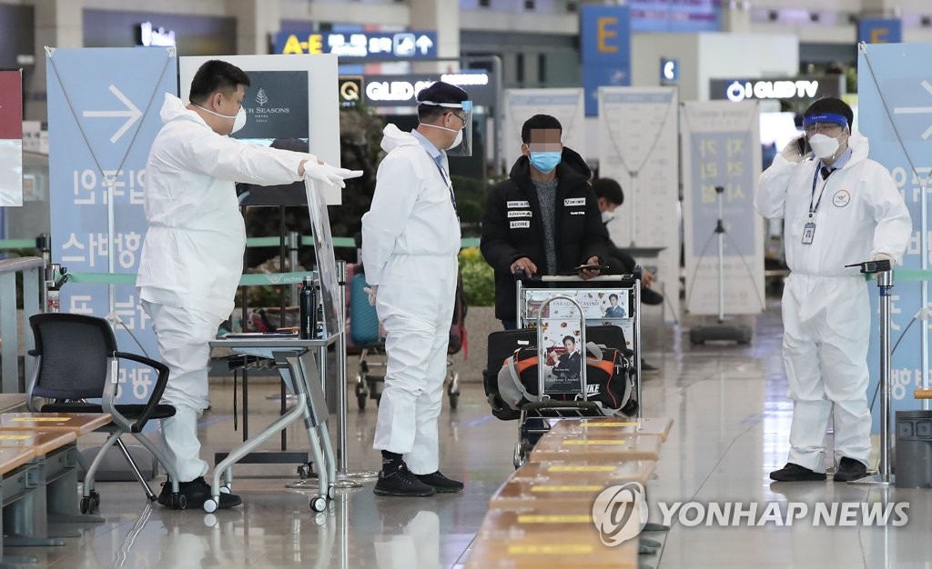 仁川国際空港で防護服を着た関係者が入国者を案内している＝２８日、ソウル（聯合ニュース）