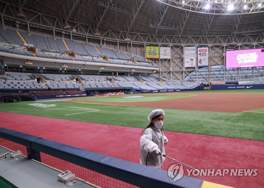 In this file photo from April 2, 2021, a health worker disinfects the railing at the first base dugout at Gocheok Sky Dome in Seoul. (Yonhap)